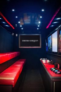 interior of gaming van showing the two levels of seating and the consoles on the cabinets