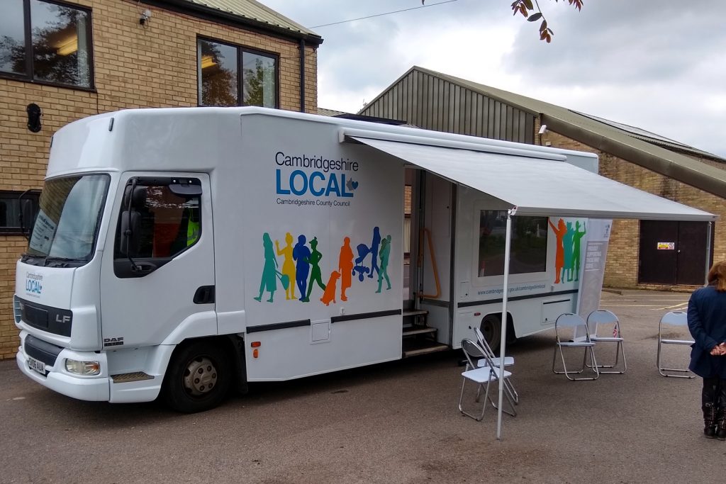 external view of a large outreach vehicle which features a large screen fitted to the body, a wind out awning and anentrance door with integral wheelchair lift