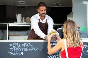 youn lady being served a burger from a catering trailer