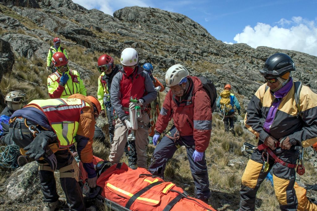 Group of rescuers carrying stretcher down mountain