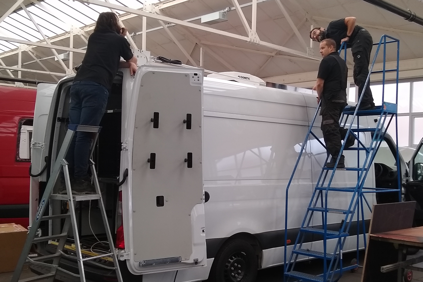 three people working on a vehicle conversion
