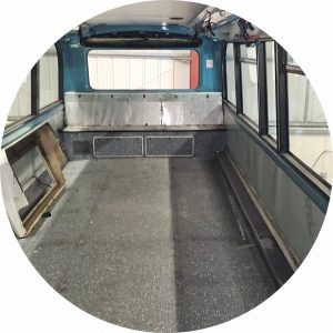 A photo of the upper deck of a bus conversion at its very early stage. The seating has been removed and some cabling is seen hanging down. It looks very bare and dirty. Hard to believe that within a few weeks this will be a vibrant youth vehicle.