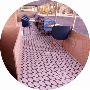 This is a 3D computerised visual showing the upper deck of a doble deck bus conversion. It illustrates some luxurious seating at small round tables and wes designed for a client wishing to offer their customers samples of their new fine cuisine. There is a black and white patterned floor covering to enhance the feelign od luxury.