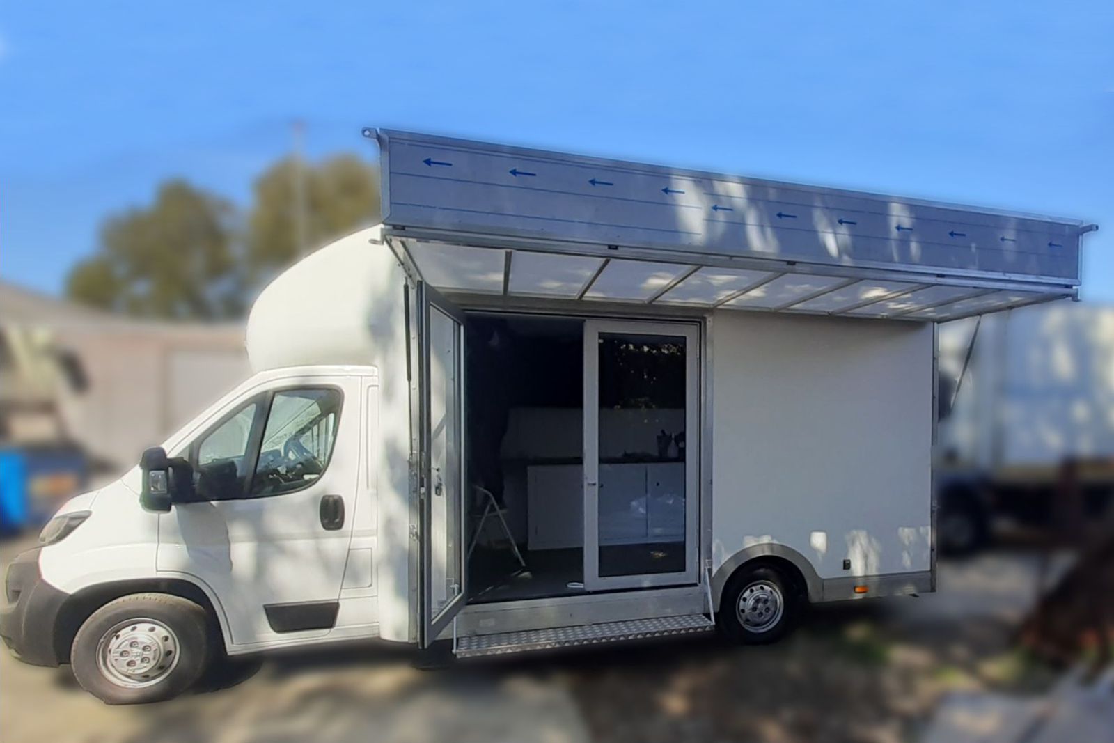 Exterior vies from the nearside showing an exhibition vehicle with a hinge up canopy and banner board. There is a double glazed access door
