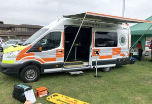 side of a panel van with the side door open and a wind out awning open running the length of the vehicle.