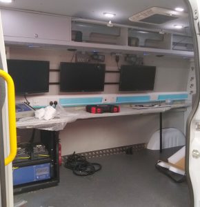 Interior view of a surveillance vehicle in build with work top installed plus three screens and overhead wall mounted cupboards