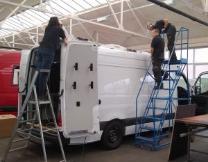 A photo of the rear of a 3500 kgs van being fitted in the factory with a hinged communications aerial. Three people can be seen undertaking the installation.