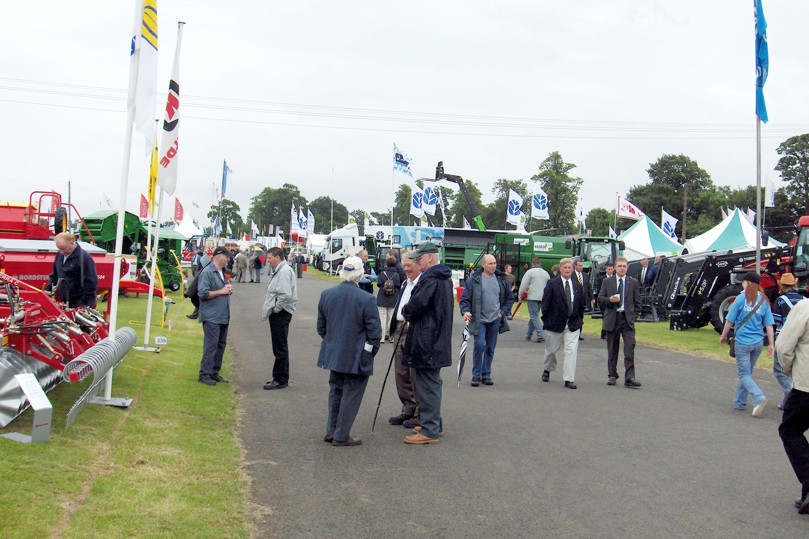 visitors walking and chatting in an aisle at the Royald Highland Show with stands in the background