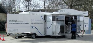 A Uk government run roadshow trailer all in white finish with display panels and a fully glazed frontage.