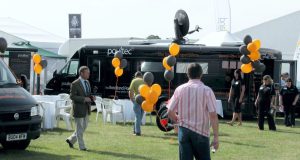 Two small bus conversions parked slightly apart to create a suare exhibition space featuring tables and chairs.