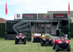 A large black painted articulated exhibition trailer shows how perfect it is for the backdrop to display large off road quad bikes on outdoor exhibition stands.
