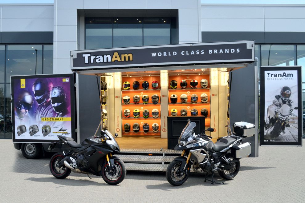 An exhibition vehicle with two swing out display panels to show a wide open interior in which are displayed rows of motorcycle helmets