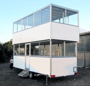 A double-deck commentary box trailer with glazing fully around each level. There is a single personnel access door on the nearside. This photo is taken from the nearside rear.