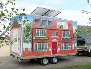 A 4 metre bespoke exhibition trailer seen from the offside to illustrate the quality and effect of applying a full vinyl graphics wrap. This shows the exterior of a house fitted with solar panels on the roof.