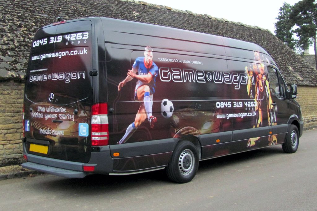 The exterior of a long wheel base Mercedes Sprinter showing a full vehicle vinyl wrap featuring figures from gaming videos