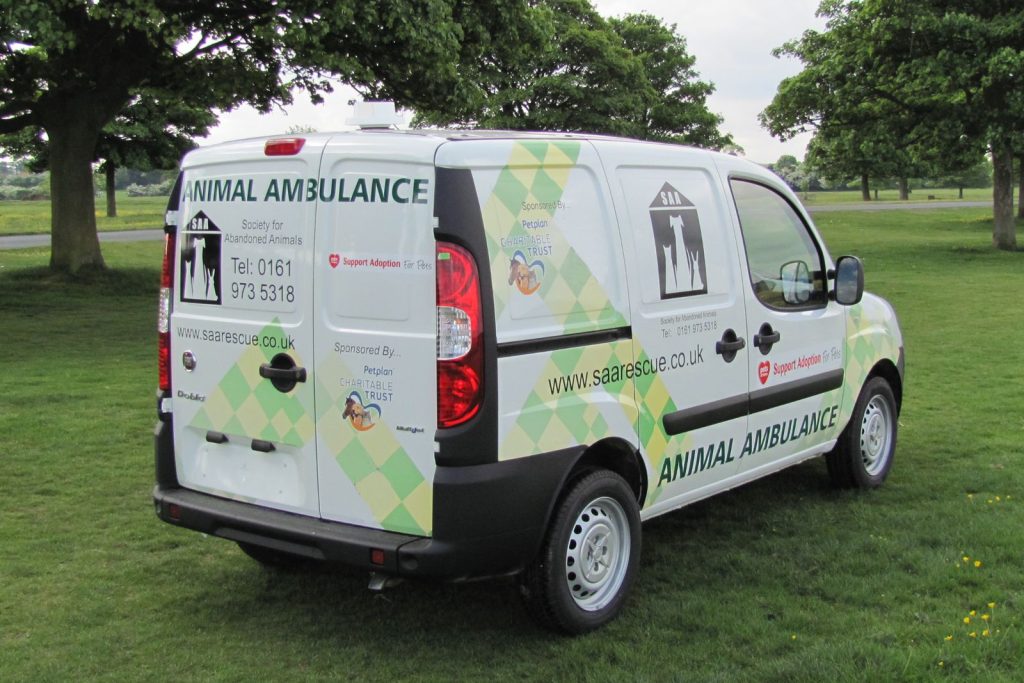 The exterior view from the rear of a dog van conversion for an abandoned animal charity. This is a small van with rear doors closed to show the exciting array of graphics and sponsors.