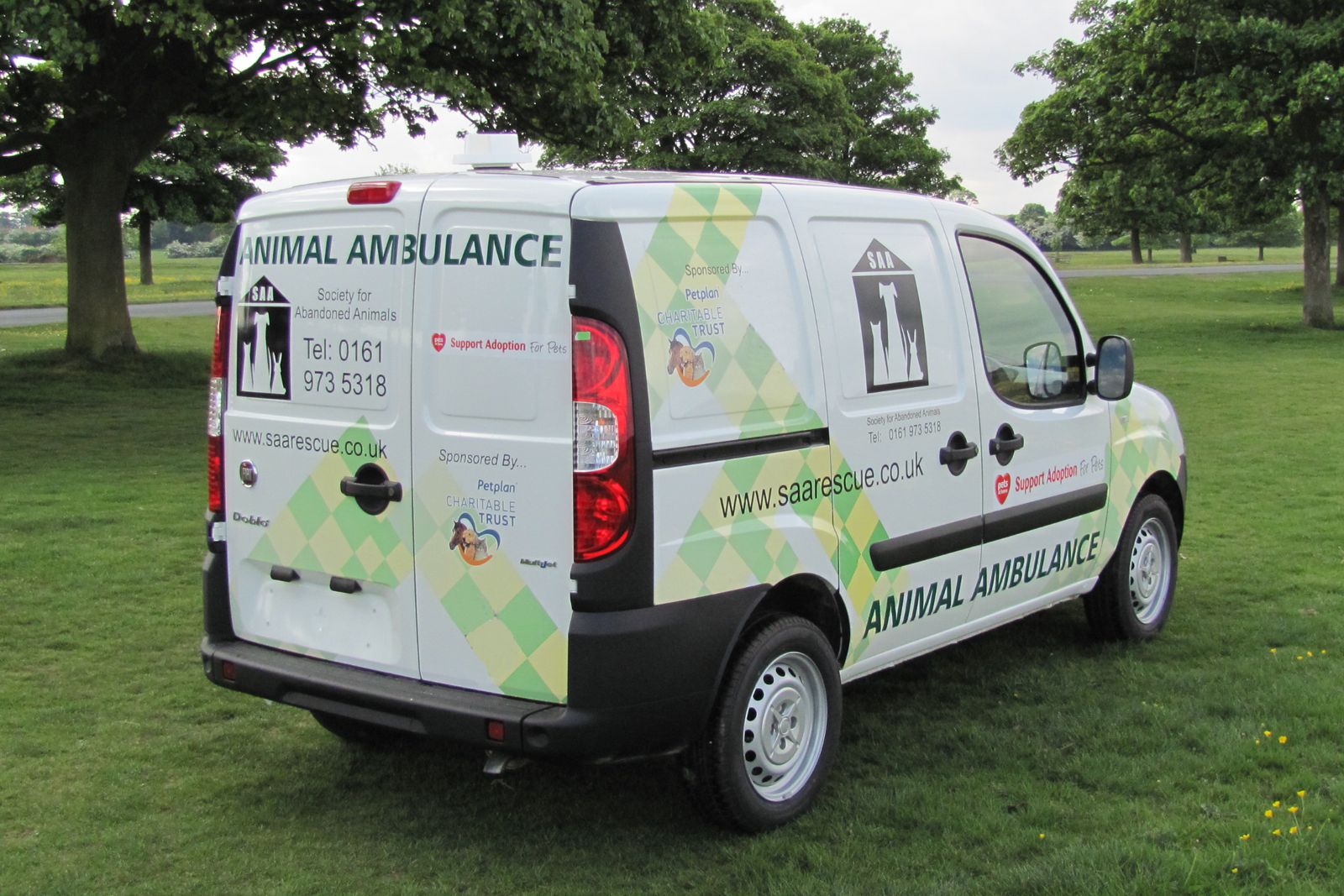 The exterior view from the rear of a dog van conversion for an abandoned animal charity. This is a small van with rear doors closed to show the exciting array of graphics and sponsors.