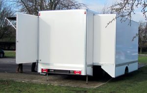 A self-supporting slide-out pod in an expandable exhibition vehicle